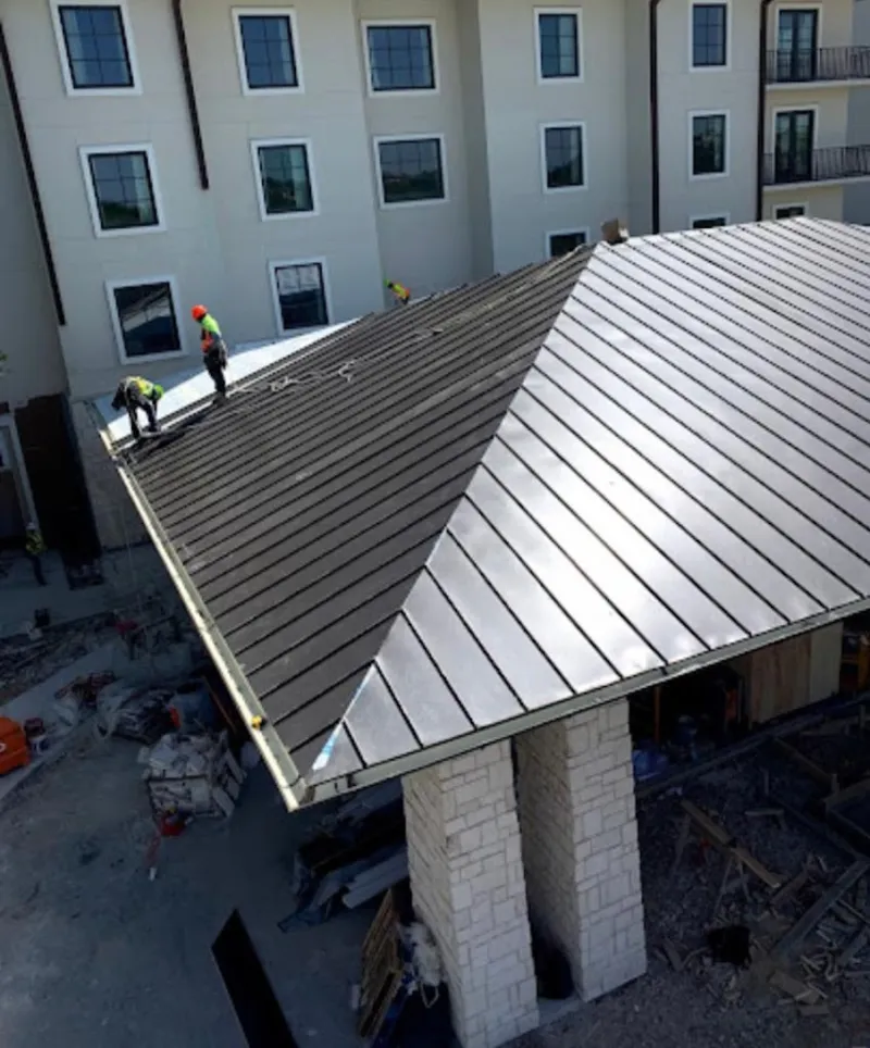 Crew installing standing seam metal roof panels on a commercial project in Cumberland